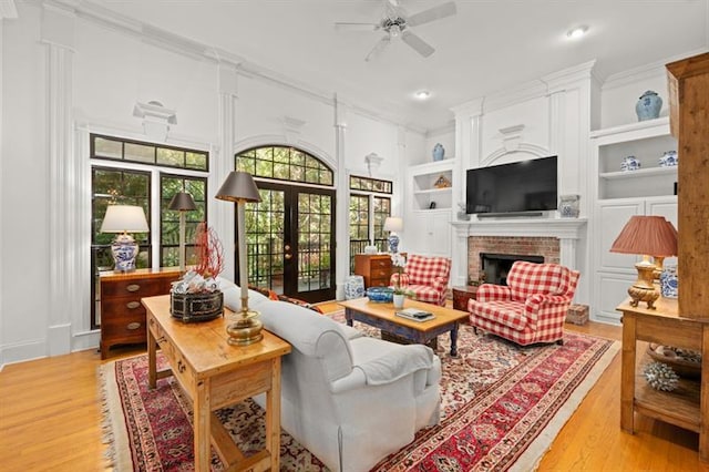 living room featuring light hardwood / wood-style floors, built in features, crown molding, and french doors