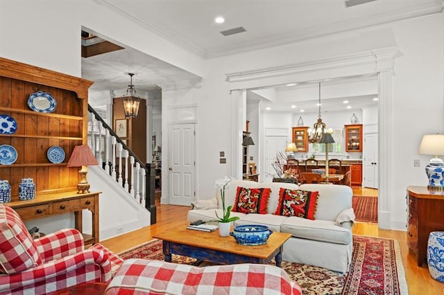 living room featuring light hardwood / wood-style flooring, a notable chandelier, and crown molding