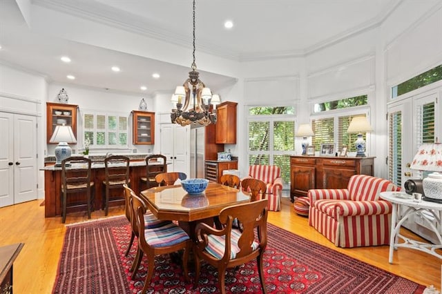 dining space with light hardwood / wood-style floors, an inviting chandelier, a wealth of natural light, and crown molding