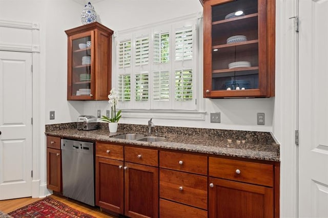 kitchen featuring dishwasher, hardwood / wood-style floors, dark stone counters, and sink