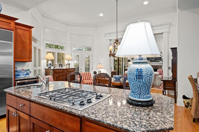 kitchen with stainless steel appliances, sink, stone countertops, light hardwood / wood-style floors, and an island with sink