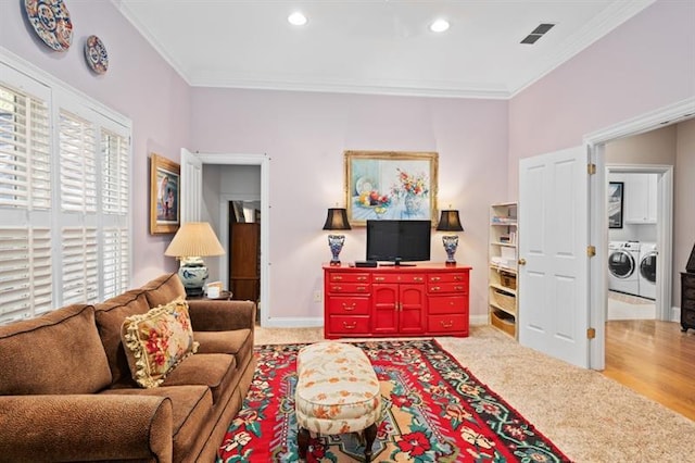 carpeted living room featuring washing machine and clothes dryer and ornamental molding