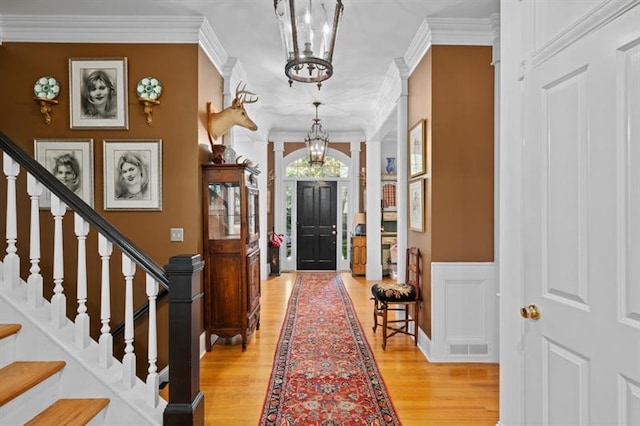 foyer featuring a chandelier, ornate columns, ornamental molding, and light hardwood / wood-style flooring