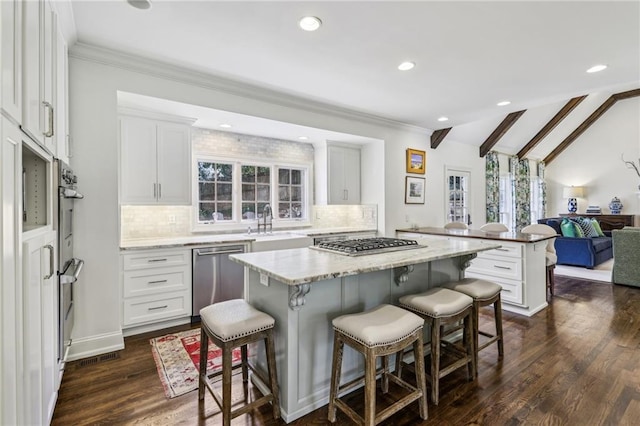 kitchen featuring lofted ceiling with beams, stainless steel appliances, a kitchen breakfast bar, and a center island