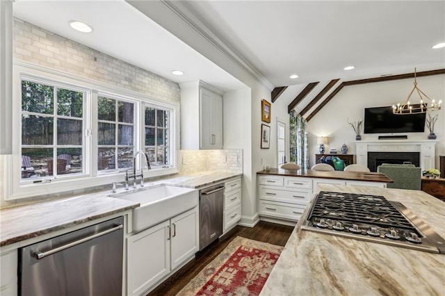 kitchen featuring a healthy amount of sunlight, light stone counters, stainless steel appliances, and a sink