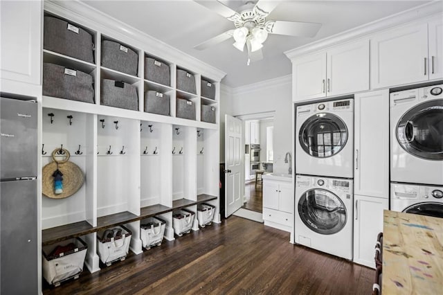 laundry room featuring stacked washer and dryer, dark wood-style flooring, a sink, cabinet space, and crown molding