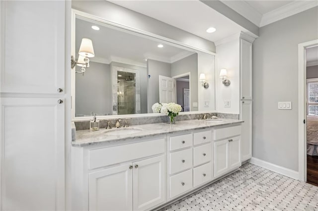 ensuite bathroom featuring a stall shower, crown molding, baseboards, and a sink