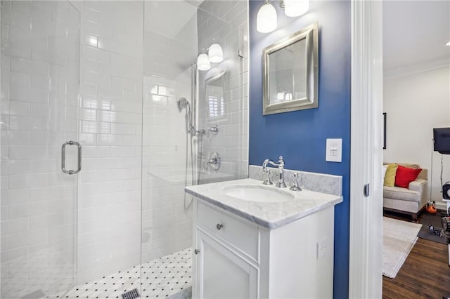 bathroom featuring connected bathroom, ornamental molding, wood finished floors, vanity, and a shower stall