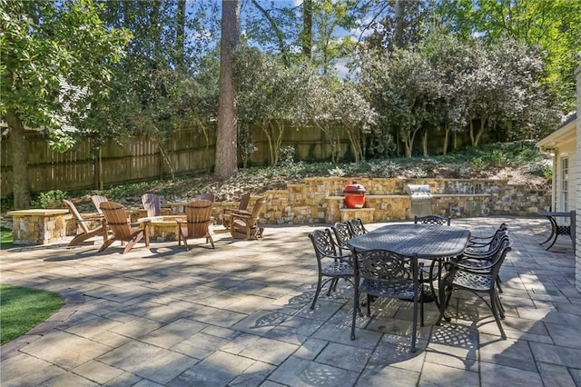 view of patio featuring a fire pit, fence, and outdoor dining space