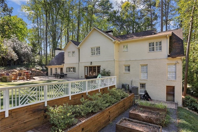 back of property featuring a garden and brick siding