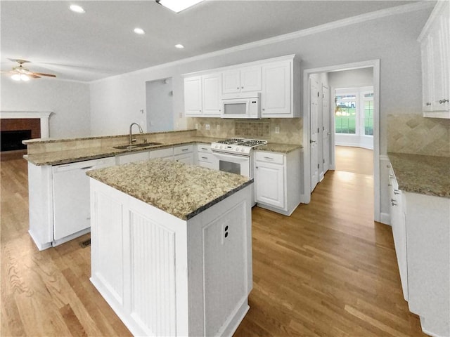 kitchen featuring ceiling fan, sink, kitchen peninsula, white appliances, and white cabinetry