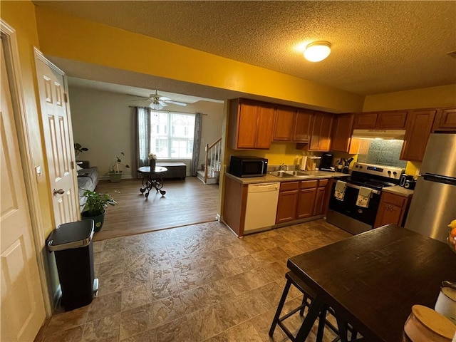 kitchen with stainless steel appliances, sink, ceiling fan, a textured ceiling, and light hardwood / wood-style flooring