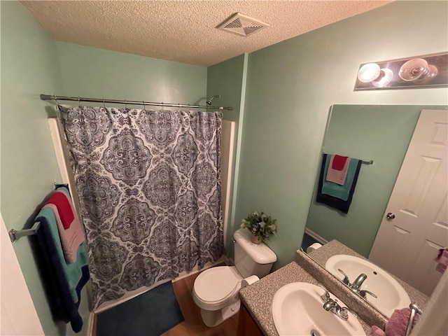 bathroom with toilet, vanity, and a textured ceiling