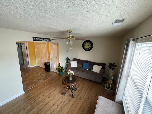 living room with ceiling fan, wood-type flooring, and a textured ceiling