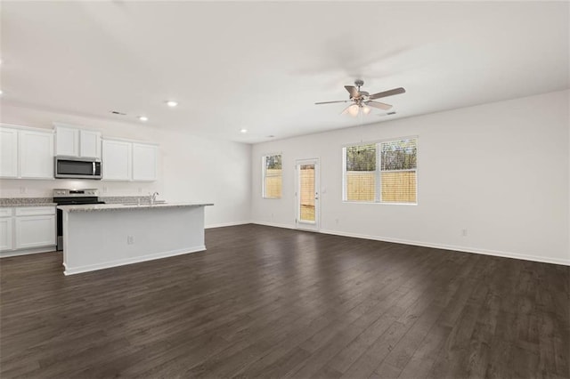 unfurnished living room featuring dark wood-type flooring, ceiling fan, and sink