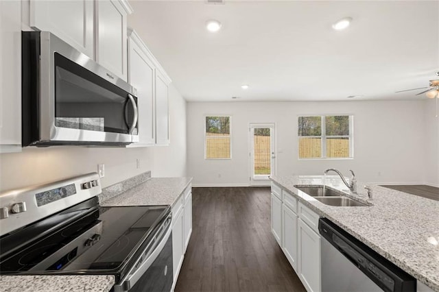 kitchen with dark wood-type flooring, sink, stainless steel appliances, light stone countertops, and white cabinets