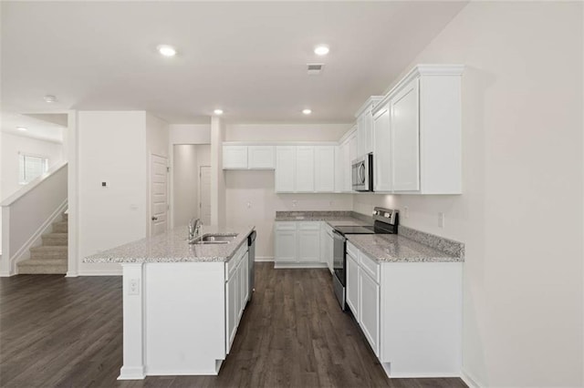 kitchen with sink, white cabinetry, light stone counters, appliances with stainless steel finishes, and an island with sink