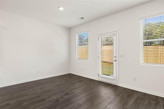 spare room with a healthy amount of sunlight and dark hardwood / wood-style floors