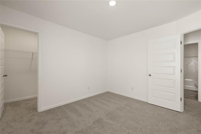 unfurnished bedroom with a walk in closet, carpet floors, and a closet