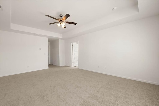 carpeted empty room with a tray ceiling and ceiling fan