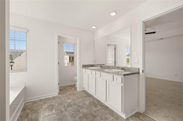 bathroom featuring ceiling fan, vanity, toilet, and a bathtub