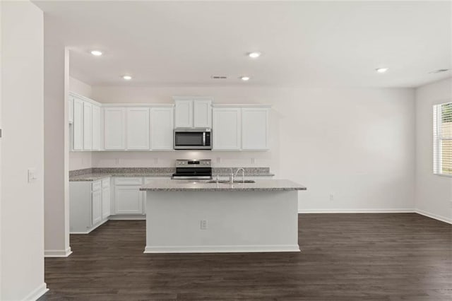 kitchen with white cabinets, a kitchen island with sink, stainless steel appliances, light stone countertops, and dark wood-type flooring