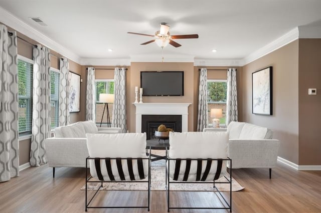 living room featuring ornamental molding, ceiling fan, and light wood-type flooring