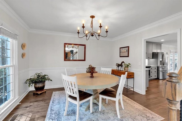 dining space featuring an inviting chandelier, wood finished floors, and ornamental molding