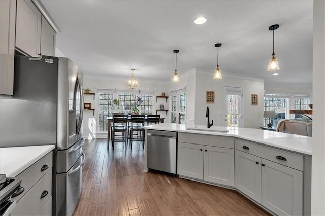 kitchen with a sink, a chandelier, light countertops, stainless steel appliances, and dark wood-style flooring