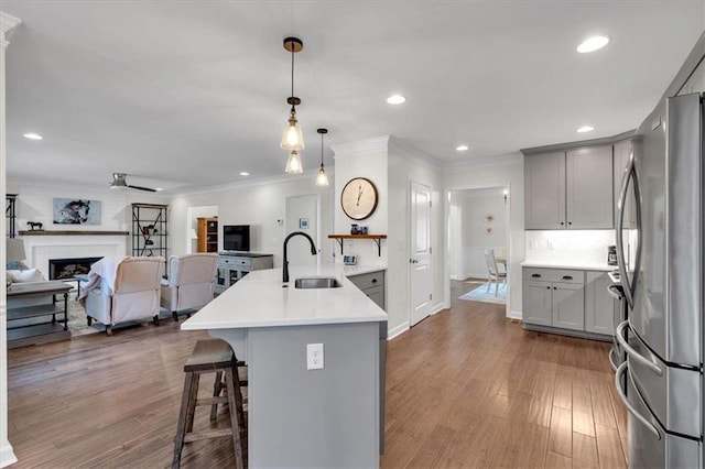 kitchen featuring a sink, open floor plan, freestanding refrigerator, a peninsula, and a breakfast bar area