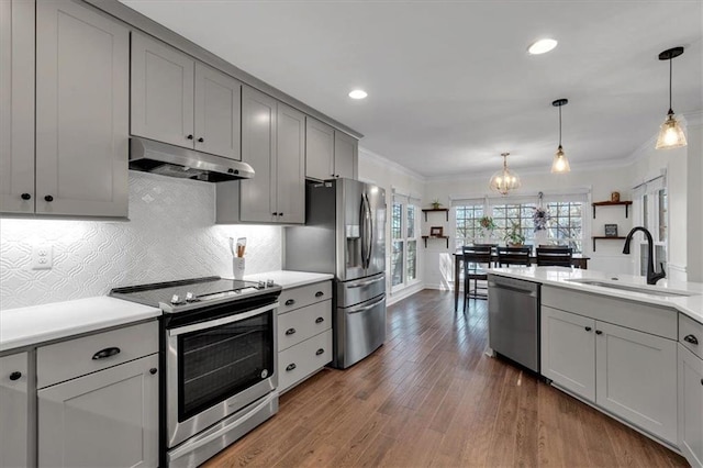 kitchen featuring gray cabinetry, a sink, under cabinet range hood, appliances with stainless steel finishes, and crown molding