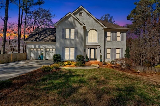 view of front of home with fence, a yard, concrete driveway, a garage, and brick siding