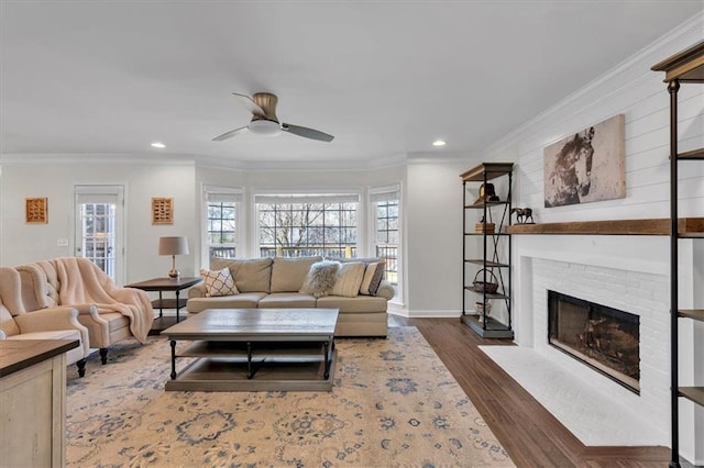 living area with a fireplace, wood finished floors, a ceiling fan, and ornamental molding