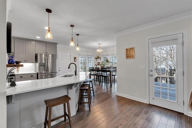 kitchen with a breakfast bar area, ornamental molding, gray cabinets, stainless steel refrigerator with ice dispenser, and a sink