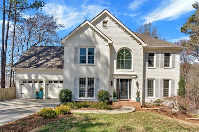 view of front facade featuring brick siding, an attached garage, concrete driveway, and fence