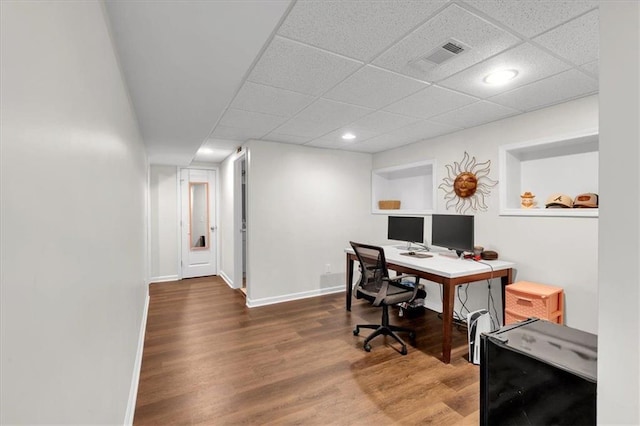 office featuring a paneled ceiling, wood finished floors, visible vents, and baseboards