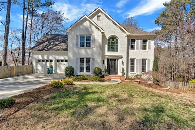 view of front facade with fence, driveway, an attached garage, a front lawn, and brick siding