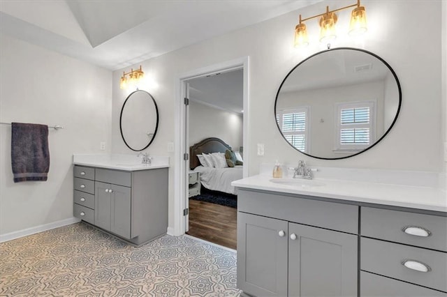 ensuite bathroom featuring ensuite bathroom, two vanities, baseboards, and a sink