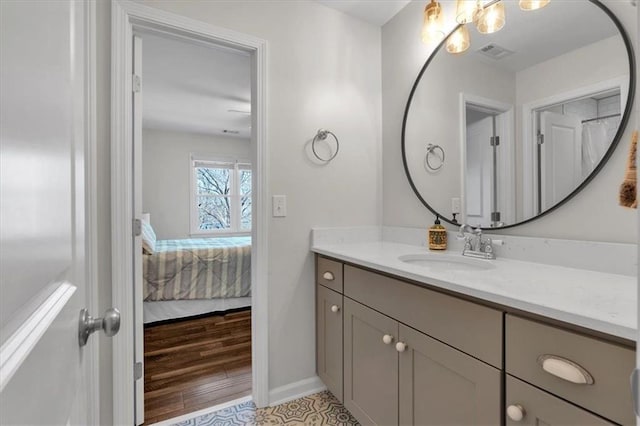 bathroom with visible vents, connected bathroom, baseboards, wood finished floors, and vanity