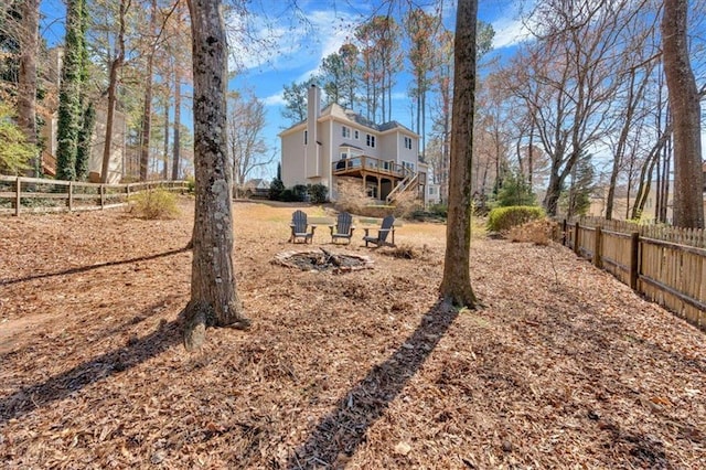 view of yard featuring a wooden deck, an outdoor fire pit, and fence