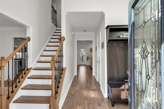 foyer entrance featuring crown molding, stairway, wood finished floors, and baseboards