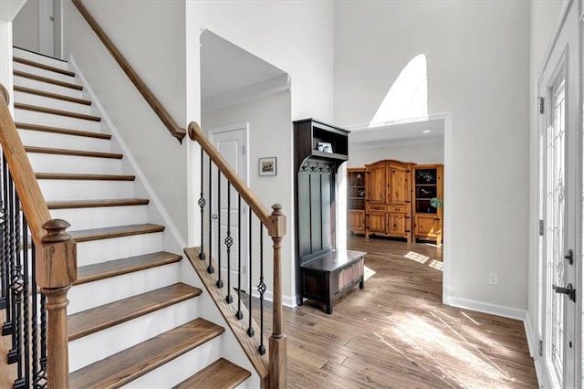 entryway with stairs, wood finished floors, baseboards, and a towering ceiling