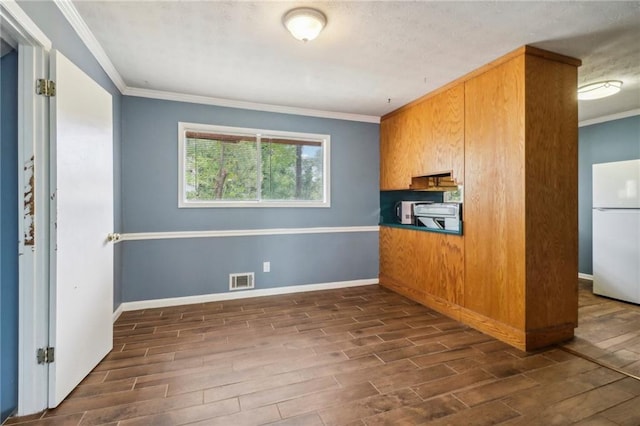 kitchen with ornamental molding, stove, dark wood-type flooring, and white fridge