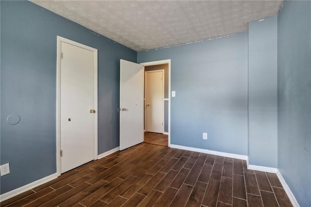 empty room featuring a textured ceiling and dark hardwood / wood-style flooring