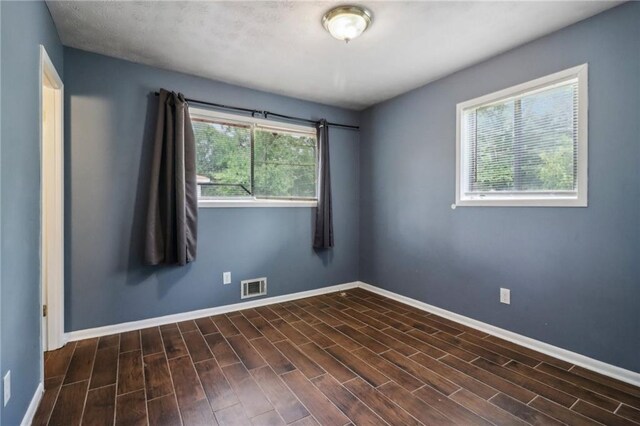 unfurnished room featuring dark hardwood / wood-style flooring and plenty of natural light