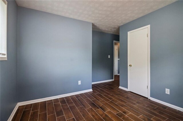 unfurnished room featuring a textured ceiling and dark hardwood / wood-style floors