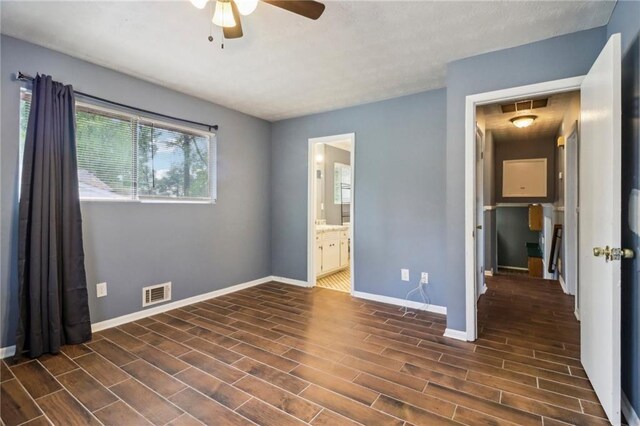 unfurnished bedroom with ceiling fan, ensuite bathroom, and dark wood-type flooring