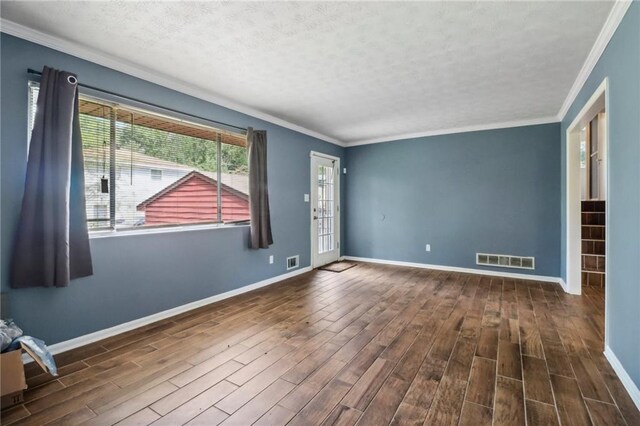 spare room featuring a textured ceiling, ornamental molding, and dark hardwood / wood-style flooring