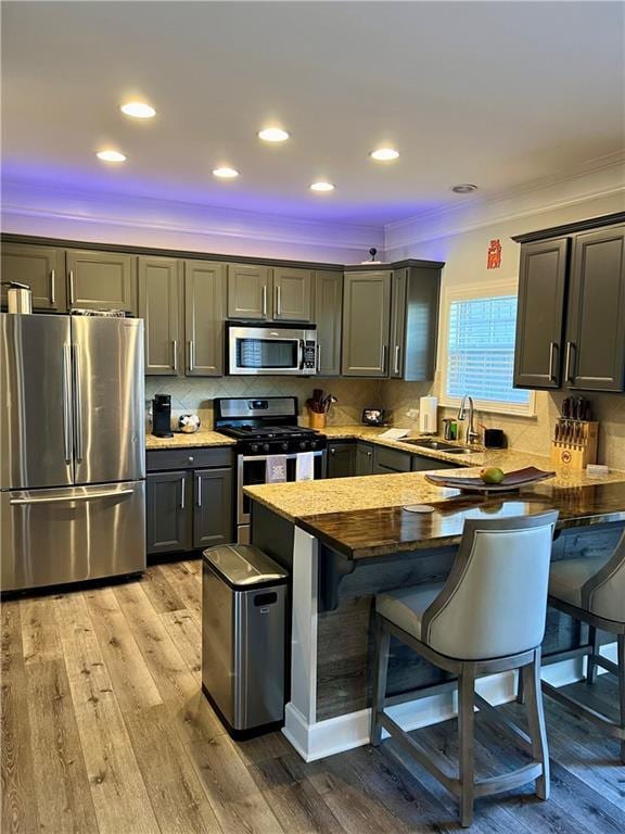 kitchen with sink, wood-type flooring, stainless steel appliances, and a breakfast bar area