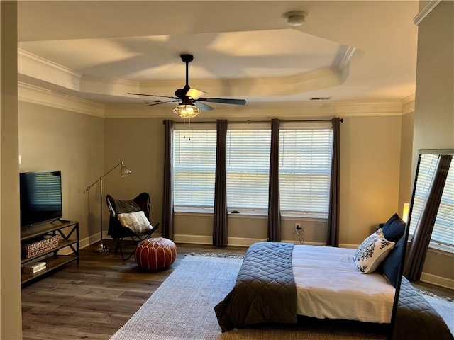 bedroom with ceiling fan, multiple windows, and a tray ceiling